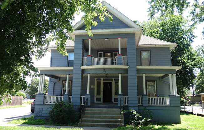 A two-story house with a front porch and a staircase leading to the entrance.