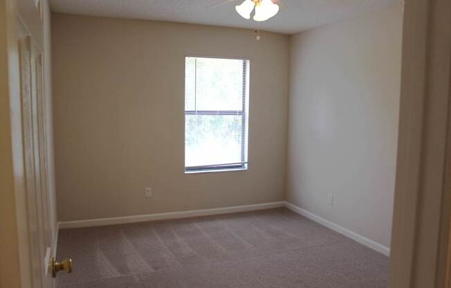 A room with a window and a ceiling fan.