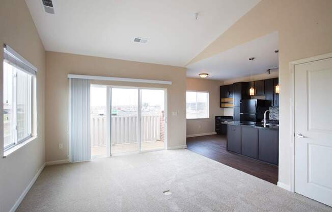 A spacious living room with a sliding glass door leading to a balcony.