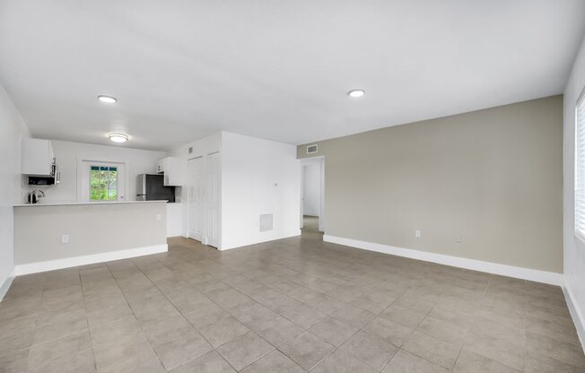 the living room and kitchen in a new home with white walls and tile flooring