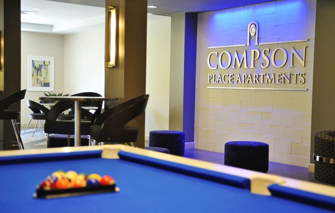 a pool table in a room with the compton place apartments logo on the wall