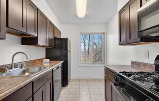 A kitchen with brown cabinets and black appliances.