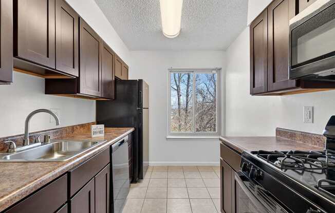 A kitchen with brown cabinets and black appliances.