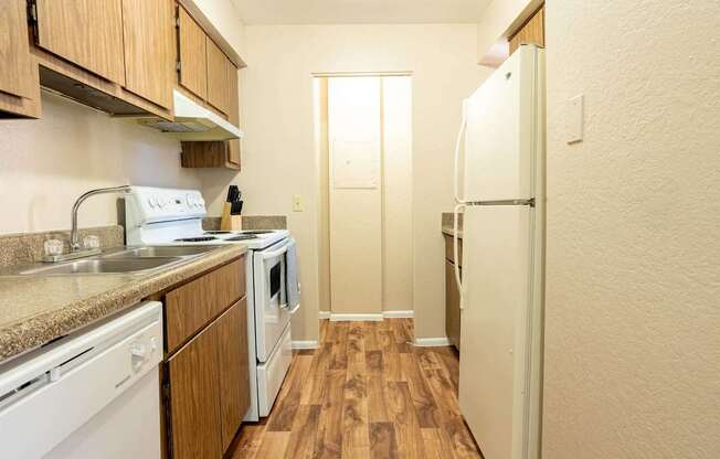 A kitchen with white appliances and wooden cabinets.
