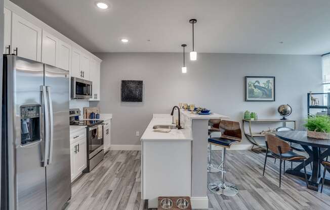 an open kitchen and dining area with stainless steel appliances and a table and chairs