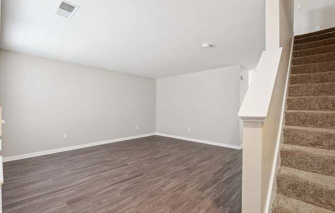 A room with a staircase and wooden flooring.