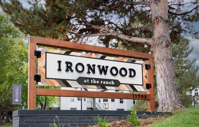 A sign that says Ironwood at the ranch with a tree behind it.