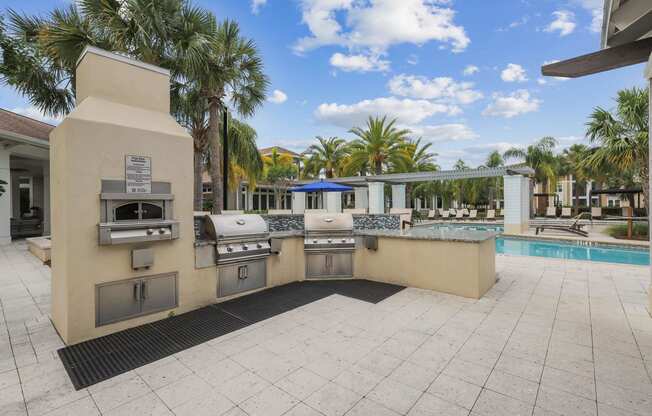 a barbecue grill is next to a swimming pool with palm trees