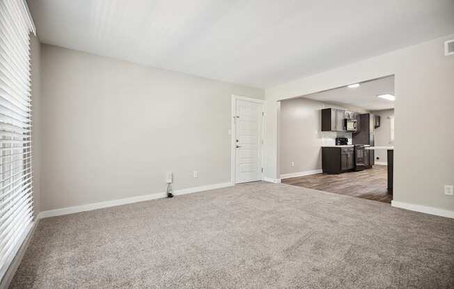 an empty living room with carpet and a kitchen at Shellbrook Apartments in Raleigh NC