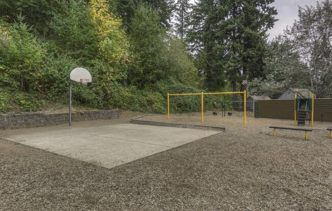 a basketball court in a park with a basketball hoop and a playground