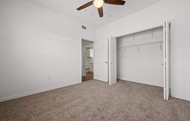 A room with a ceiling fan and carpeted floor.