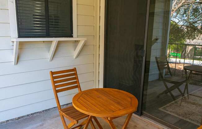 A wooden chair and table are on a patio.