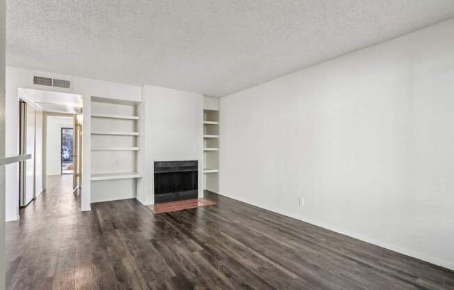 A room with a fireplace and wood flooring.