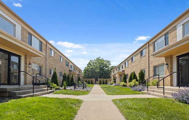 Courtyard view between mid-century style Monon Court apartment buildings featuring landscaping and sidewalk in Broad Ripple