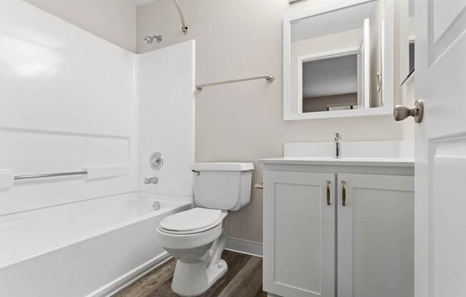 A white toilet sits in a bathroom next to a white bathtub.