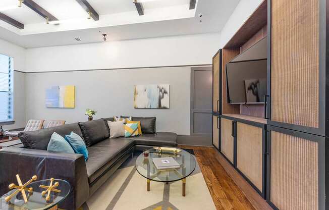 a living room with a large black couch and a glass coffee table