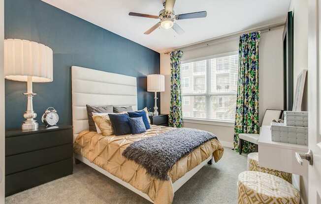 A bedroom with a bed, a ceiling fan, and a window with curtains.