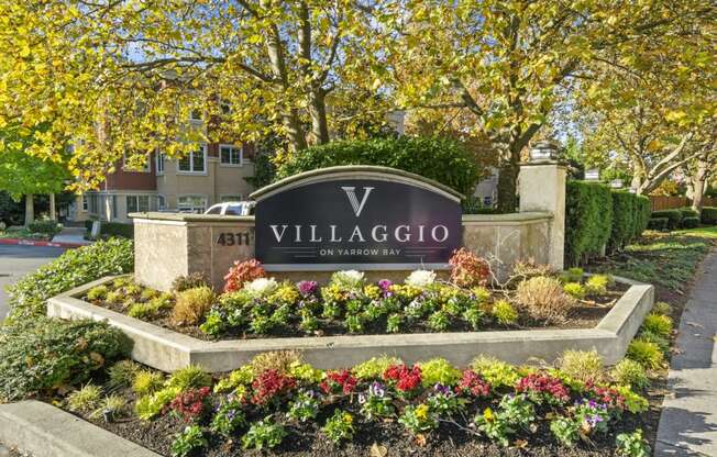 a sign for villaggio on ardennes boulevard with flowers in front of it