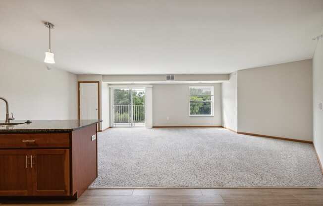 an empty living room and kitchen with wood flooring and a window