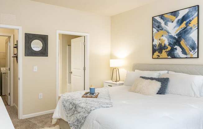 a bedroom with a white bed and a painting on the wall
