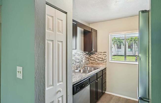 A kitchen with a white door and a window with blinds.