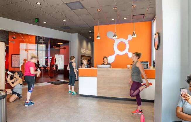 A gym with orange walls and people exercising.