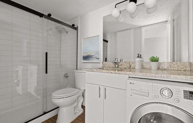A white toilet is in a bathroom with a washer and dryer.