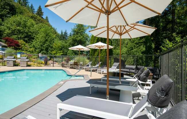 a swimming pool with tables and umbrellas next to it