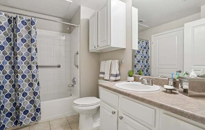 Windsor bathroom with a white toilet and a shower curtain and a sink at Encore at Buckingham Apartments in Richardson, TX