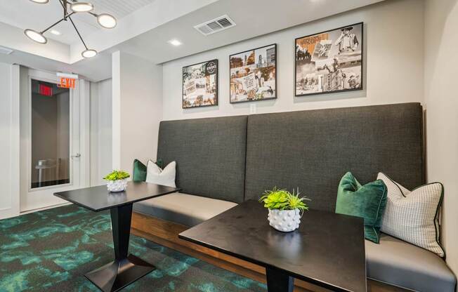 A black table with a potted plant on it sits in front of a grey couch.