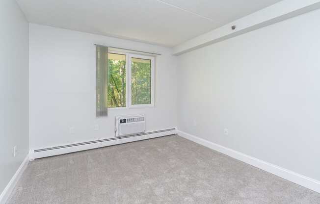 an empty living room with white walls and a window