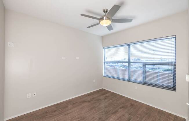 A room with a ceiling fan and a window with blinds.
