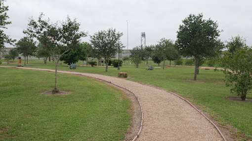 A park with a dirt path and green grass.