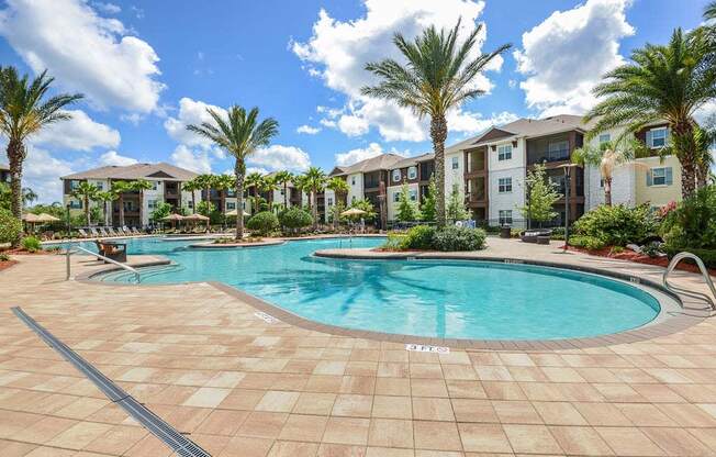 a swimming pool with palm trees in front of an apartment complex  at Cabana Club - Galleria Club, Florida, 32256