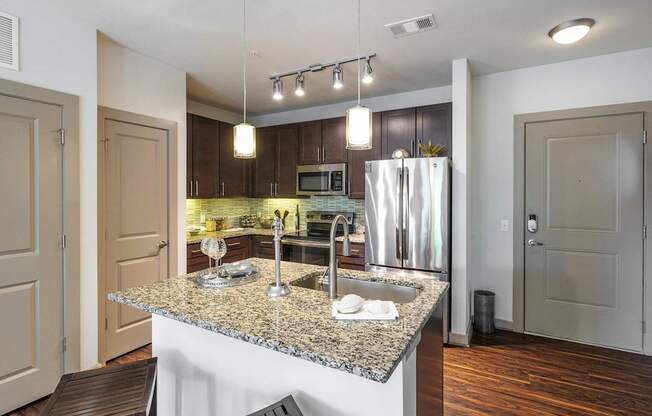 A modern kitchen with granite countertops and stainless steel appliances.