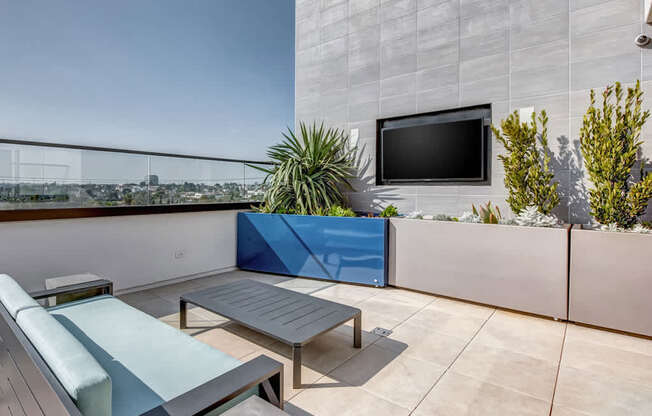 A modern balcony with a blue cushion and a flat screen TV.