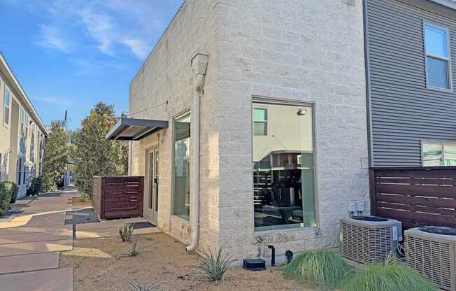 a side view of a building with a sidewalk and plants