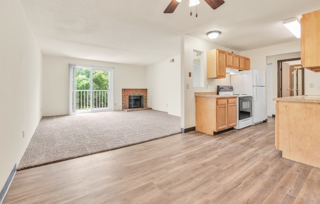 A living room with a fireplace and a kitchen area in the background.