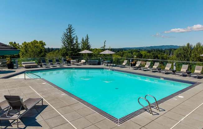 A large swimming pool surrounded by lounge chairs and umbrellas.