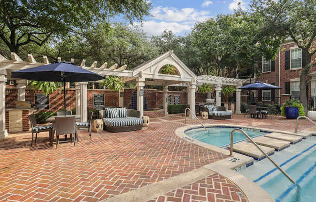 A pool area with a brick patio and a small pool.