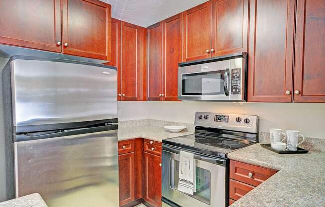 A kitchen with wooden cabinets and a stainless steel refrigerator.