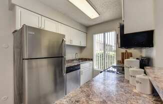 Kitchen with stainless steel appliance package, white cabinetry and ample counter space