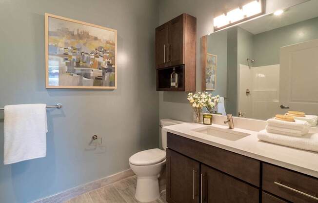 A bathroom with a toilet, sink, and a painting on the wall.