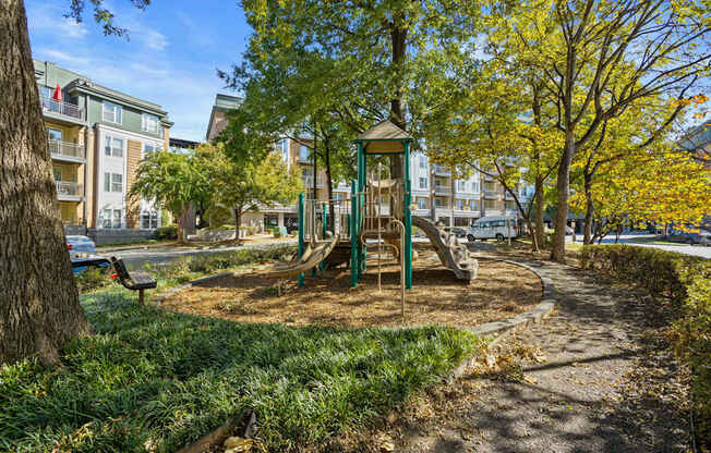 Flatiron West Trade Apartments playground with slides, mulch and a bench.