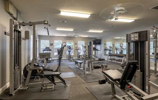 A gym with a variety of equipment including a rowing machine, a bench press, and a squat rack.