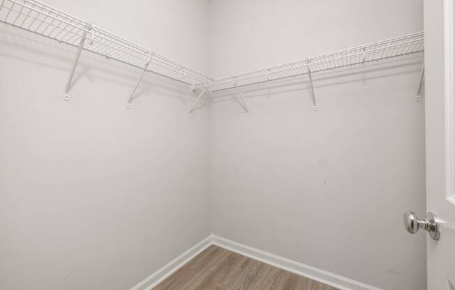 a room with white walls and a white closet with hanging racks