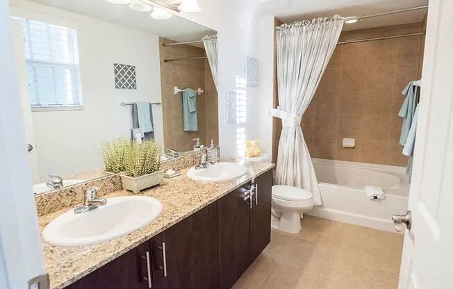 A bathroom with a sink, mirror, toilet, and bathtub.