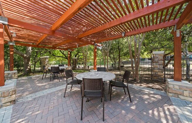 a patio with a pergola and a table and chairs