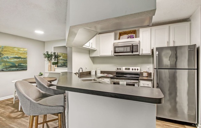 a kitchen with stainless steel appliances and a counter with chairs