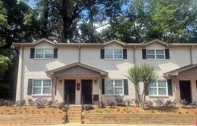 A two-story house with a red door and a small front yard.